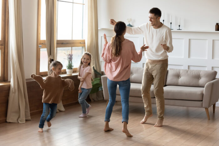 Happy family with little kids dancing in living room