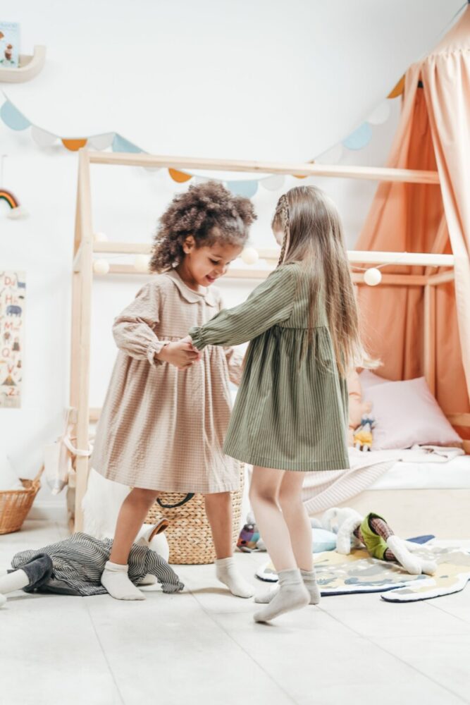 Zwei Mädchen tanzen im Kinderzimmer.